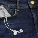 En kondom og hørertelefoner der stikker op fra en persons forlomme