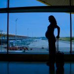 Gravid kvinde der står i lufthavnen og skal rejse